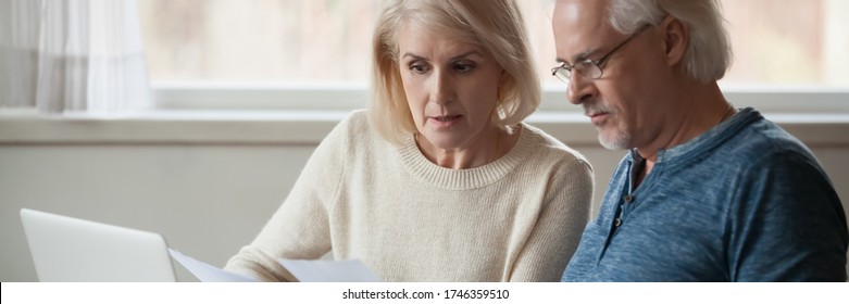 60s Spouses Serious Couple Read Financial Statement Papers Analyzing Family Expenses Feels Concerned. Bank Debt, Overspend, Finance Problems Concept. Horizontal Photo Banner For Website Header Design