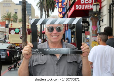 6-18-2019 Hollywood, California: A man wears silver reflective sunglasses while posing with a Hollywood Movie Click Board while on the streets on Hollywood California. Editorial Use Only.