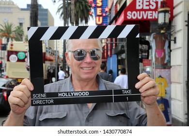 6-18-2019 Hollywood, California: A man wears silver reflective sunglasses while posing with a Hollywood Movie Click Board while on the streets on Hollywood California. Editorial Use Only.