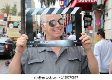 6-18-2019 Hollywood, California: A man wears silver reflective sunglasses while posing with a Hollywood Movie Click Board while on the streets on Hollywood California. Editorial Use Only.