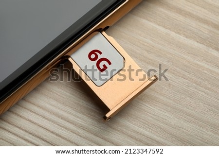 6G technology, Internet concept. SIM card in smartphone tray on wooden table, closeup