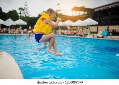 A 6-year Blond Boy In A Life Vest Jumping In The Swimming Pool Of A Hotel In Turkey