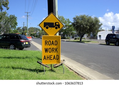 7 April 2018 Road Work Ahead Sign By The Street In Coffs Harbour, Australia. Yellow Sign Board With Picture Of Truck And Road Work Ahead Written On It At Road Work Site.