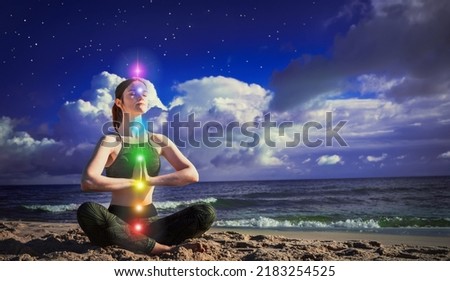 7 chakras. A woman meditates in the lotus position on the background of dark night blue sky and sea. The concept of harmony and healing. Calm