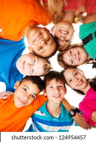 7 kids looking down standing in a circle smiling and looking down