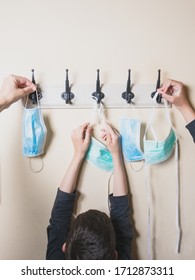 7 Year Old Boy And His Family Hanging Their Masks On A Coat Rack After Going Out After Quarantine, Prevention And End Of Quarantine Concept