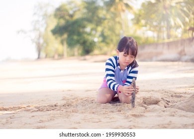 7 Years Old Asian Girl Play Sculpture White Sand On The Sea Beach.Vacation And Relax.Playful Active Kid On Beach In Summer Vacation And Child Development.Asian Kid Girl Play In Sand Beach In Thailand.