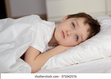 7 Years Old Boy Resting In White Bed With Eyes Open. Sleeping Boy. Sleeping Child