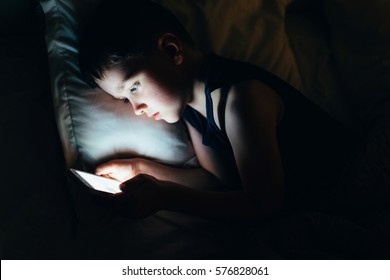 7 Years Old Child Boy Using Smartphone At Night In Bed