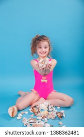 7 Years Old Child Holding Seashell On Blue Background. Focus On Seashell