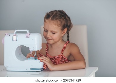 7 years old child studying work with a modern sewing machine. Hobby.