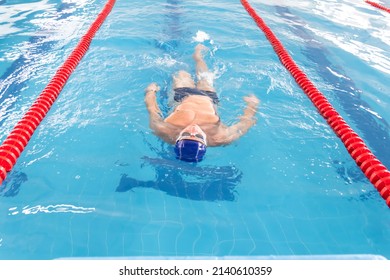 A 70-year-old pensioner is resting, swimming, recovering in the pool with clear and blue water in the hotel.