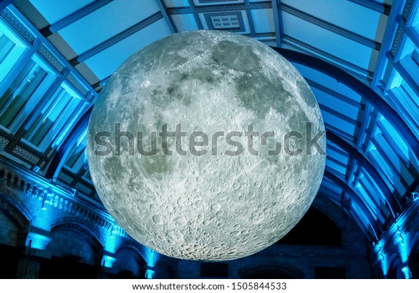 7-26-2019 London UK -3-D model of the moon\
displayed in free-to-public Natural Science Museum - hanging from\
ceiling with dramatic\
lighting