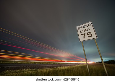 75np speed limit sign at night next to afreeway at night - Powered by Shutterstock