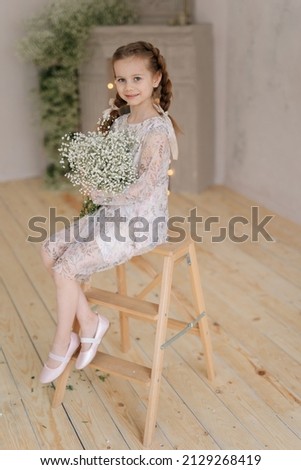 a 7-year-old girl in a dress, with a spring bouquet of gypsophila flowers, Selective focus