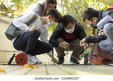 8 11 2021 University Students Of Small Group Of Boy And Girl With Face Mask Squat Down To Do Field Borehole Test Measurement Seriously During Covid-19 Omicron Period In Hong Kong