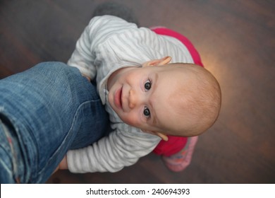 A 8 Month Old Baby Lifting Up On The Fathers Leg