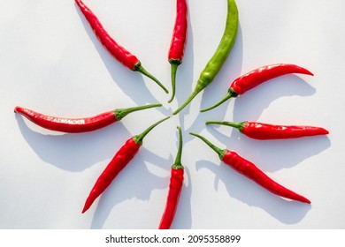 8 Red And 1 Green Raw Hot Peppers On White Paper. Stand Out Concept. Similarity Versus Difference.