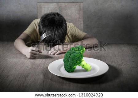 8 years old disgusted and displeased child refusing to eat healthy green broccoli feeling upset in kid nutrition education on healthy fresh food and young boy hating eating vegetarian meal