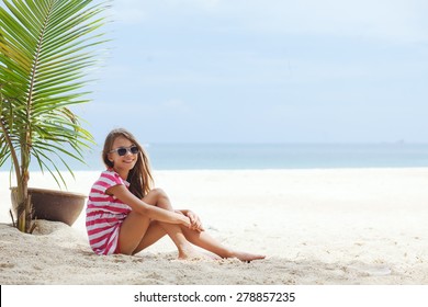 8 years old girl resting on the tropical palm beach in Thailand in summer