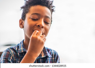 8 Years Old Kid Eating And Enjoying Some Food (not Visible) Outdoor