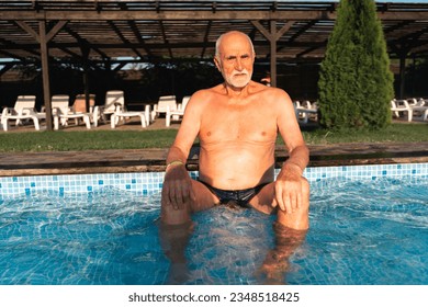 80 years old white man with beard relaxing near the pool on a hot summer sunny day. Lifestyle candid style, happy real emotions - Powered by Shutterstock