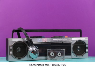 80s Retro outdated portable stereo radio cassette recorder, headphones, audio cassette on  purple background.