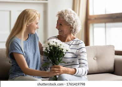 8-march International Women Day spring holiday celebration, receive congratulation and best wishes at birthday, family showing attention and love concept. Adult daughter prepare flowers for old mother - Powered by Shutterstock