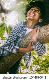 8-year-old Color Kid With Rasta Hair Plays Happy Climbing Up An Avocado Tree