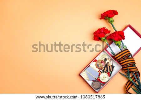 9 May background. Medals of Great patriotic war, St George's ribbon and  red carnations on orange background. Heirloom. Copy space.