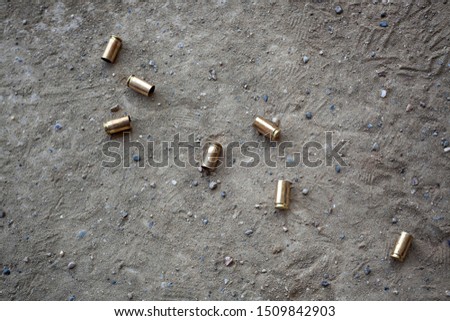 9 mm empty bullet shells lying on desert dirt with some rocks