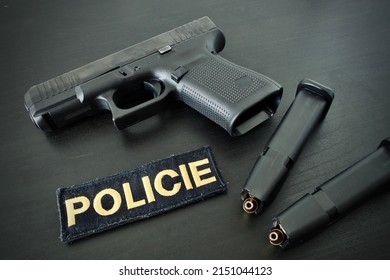 9 Mm Handgun With Two Fully Loaded Magazines And Police Velcro Badge On  Black Wooden Desk