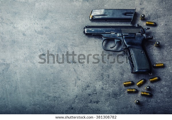 9 mm\
pistol gun and bullets strewn on the\
table.