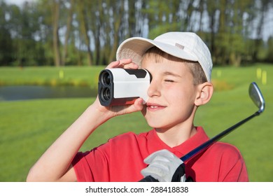 9 year boy golfer watching into rangefinder at his hit - Powered by Shutterstock