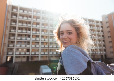 90s Vibes. Young Caucasian Blonde Girl Looking At Camera And Grinning. Block Of Flats In The Background. High Quality Photo