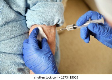A 90-year-old woman is given the covid-19 vaccine by a doctor. Vaccination of the elderly. Senior woman getting a COVID-19 vaccine at a nursing home. - Shutterstock ID 1873415005