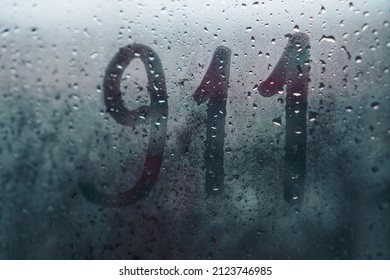 911 written on wet fogged glass on a rainy day
