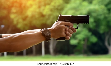 9mm Automatic Pistol Gun Holding In Hand Of Gun Shooter, Blurred Shooting Range Background, Concept For Security Training By Using Pistol Gun To Save And To Protect Human Life And Human's Property.