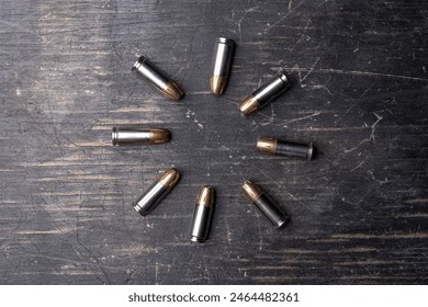9mm bullets arranged in a circular pattern on a dark wooden surface