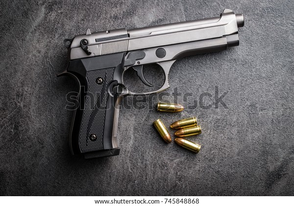 9mm pistol\
bullets and handgun on black\
table.