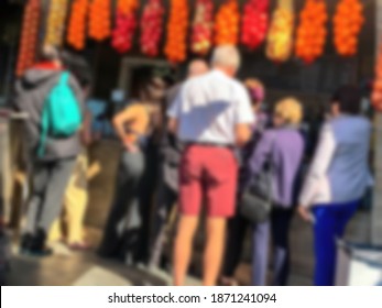,A queue of unknown people at the Kiosk selling freshly squeezed juices.Blurred view