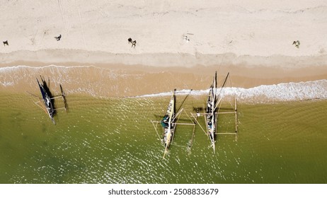 "A stunning aerial view of traditional Malagasy fishing boats (pirogues) anchored along a pristine beach. The golden sand, gentle waves, and vibrant green water create a picturesque coastal scene, hig - Powered by Shutterstock