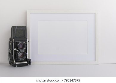 A4 A3 A5 white wooden picture frame with white blank space for your quote, logo or work or for overlay standing next to vintage camera. Blank space for bloggers, marketers or website designers.
