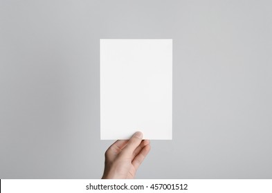 A5 Flyer / Invitation Mock-Up - Male hands holding a blank flyer on a gray background. - Shutterstock ID 457001512