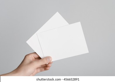 A6 Flyer / Postcard / Invitation Mock-Up - Male Hands Holding Blank Flyers On A Gray Background.