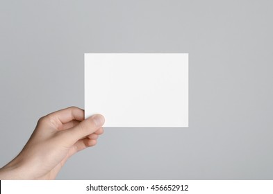 A6 Flyer / Postcard / Invitation Mock-Up - Male Hands Holding A Blank Flyer On A Gray Background.