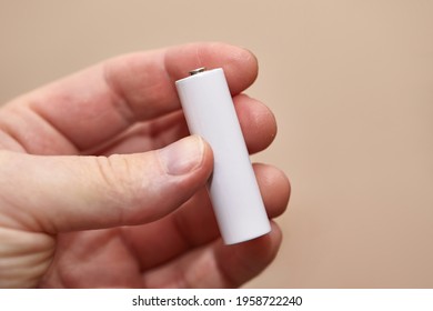 AA Battery Cell Held In Hand, Blank White Surface