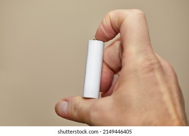 AA Battery Cell Held In Hand, Blank White Surface