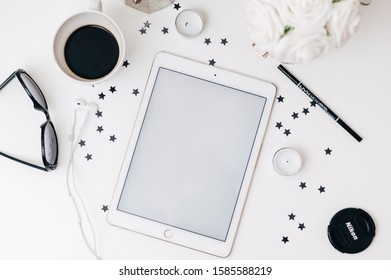 Aalborg, Denmark: IPad On Top Of White Desk, Next To Sunglasses, Black Coffee, Candles, White Roses And Stars