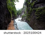 Aare Gorge, blue alpine river between narrow rocky cliffs covered with green vegetation and trees, forming a waterfall, captured at Meiringen , Switzerland.